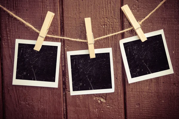 Papel fotográfico pegado a la cuerda con alfileres de ropa sobre fondo de madera —  Fotos de Stock