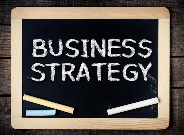 Business strategy handwritten with white chalk on a blackboard — Stock Photo, Image