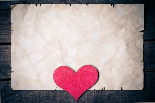 Corazón de madera sobre papel viejo — Foto de Stock