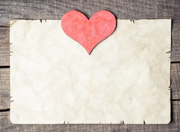 Wooden heart on old paper — Stock Photo, Image