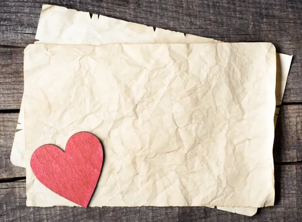 Corazón de madera sobre papel viejo — Foto de Stock
