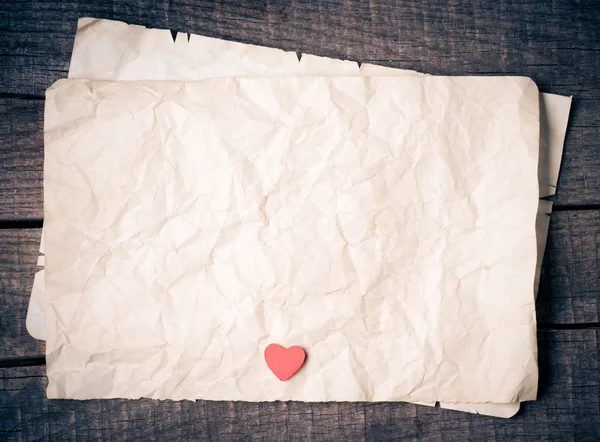 Wooden heart on old paper — Stock Photo, Image