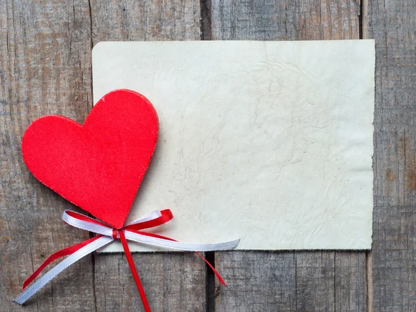 Old card on aged wood decorated with wooden heart — Stock Photo, Image