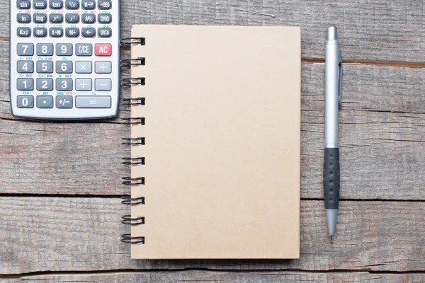 Calculadora, pluma y cuaderno sobre mesa de madera — Foto de Stock