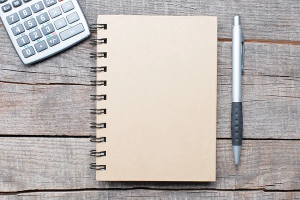 Calculadora, pluma y cuaderno sobre mesa de madera — Foto de Stock