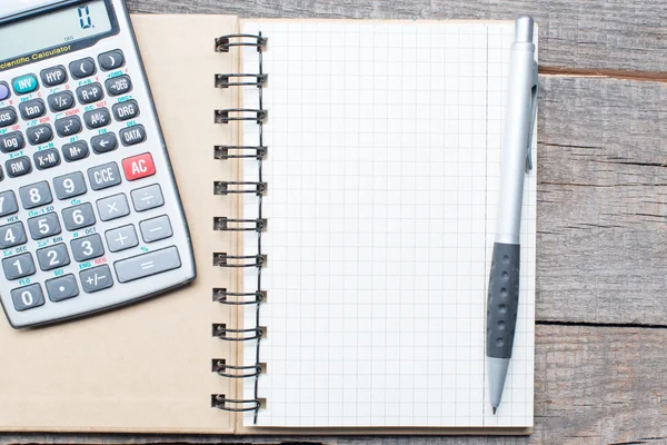 Kalkulator, pióro i notebook na drewnianym stole — Zdjęcie stockowe