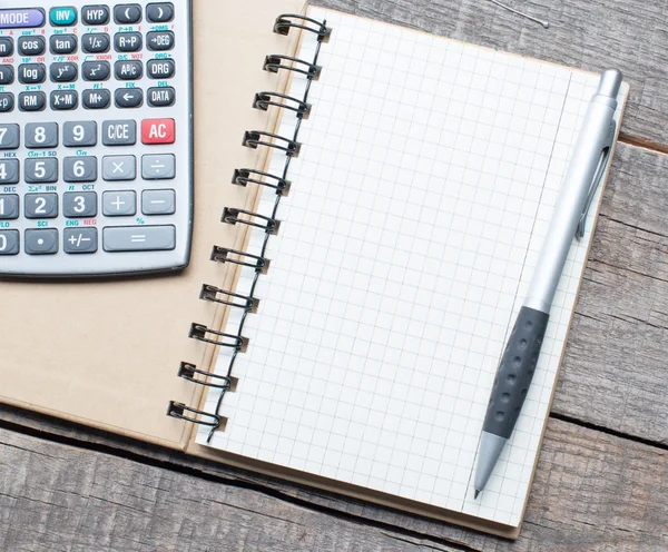 Calculadora, pluma y cuaderno sobre mesa de madera — Foto de Stock