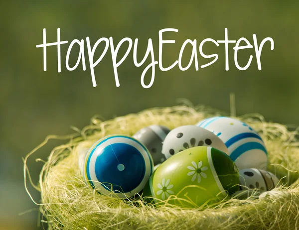 Easter eggs in wisker basket in nature with text Happy Easter — Stock Photo, Image