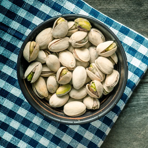 Tuercas de pistacho agrietadas y secas en un tazón de madera — Foto de Stock