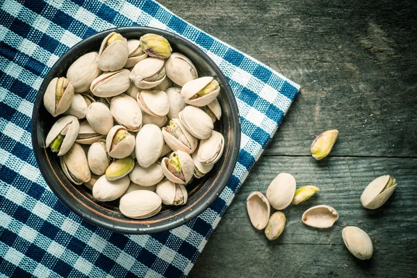 Tuercas de pistacho agrietadas y secas en un tazón de madera — Foto de Stock