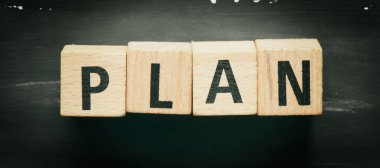 Tahta bloklar ve siyah arka plan için plan kelimesi. İş dünyasında kavram.