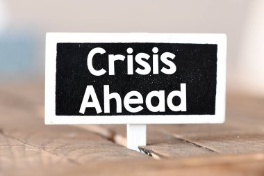 Küçük tahta üzerinde CRISIS AHEAD sözcükleri.
