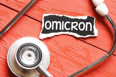 OMICRON kelime virüs steteskop yanında siyah bir kağıt parçası üzerinde.