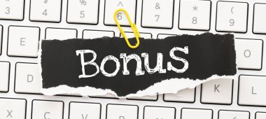 Bir bilgisayar klavyesine yerleştirilmiş küçük bir kağıt parçasındaki BONUS kelimeleri.