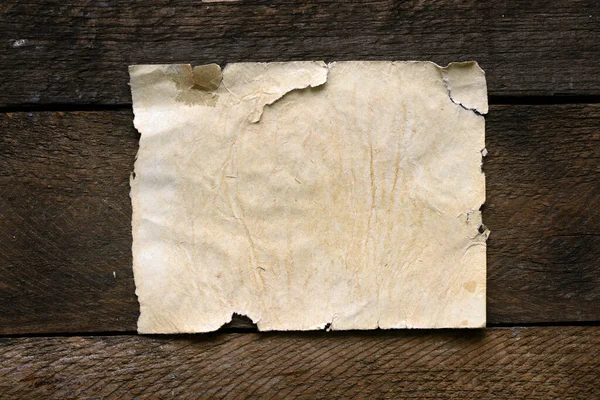 Tahta bir masanın üzerinde eski boş bir kağıt parçası..