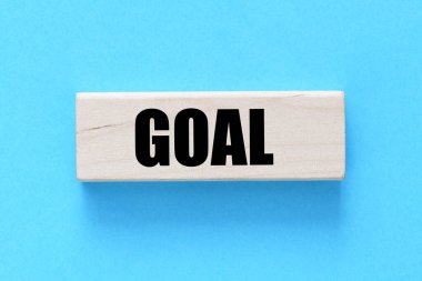 GOAL word on a wooden block and a blue background.