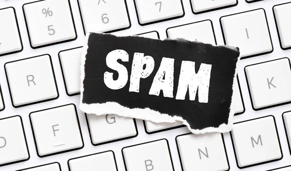 白いコンピュータのキーボード上に配置された紙の黒い部分にSpam — ストック写真