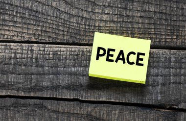 Küçük bir kağıt üzerinde barış sözcüğü ve ahşap bir arka plan.