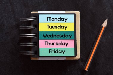 Pazartesi, salı, çarşamba, perşembe, cuma, haftanın her günü siyah arka planda bir defterde..