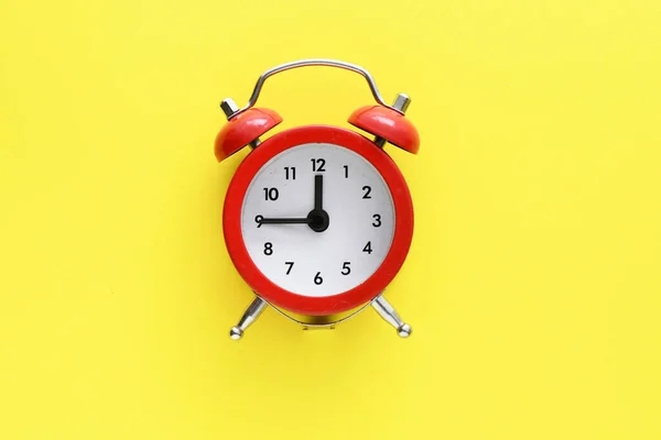 黄色の背景に赤い目覚まし時計 — ストック写真