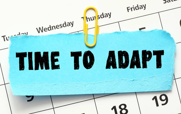 ВРЕМЯ Адаптировать слова, написанные на синем листе бумаги, помещенном в календарь. Концепция в бизнесе.