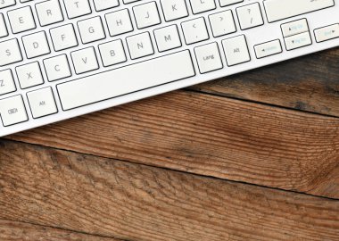 Ahşap arka plandaki beyaz bilgisayar klavyesini kapat. Yukarıdan görüntüle