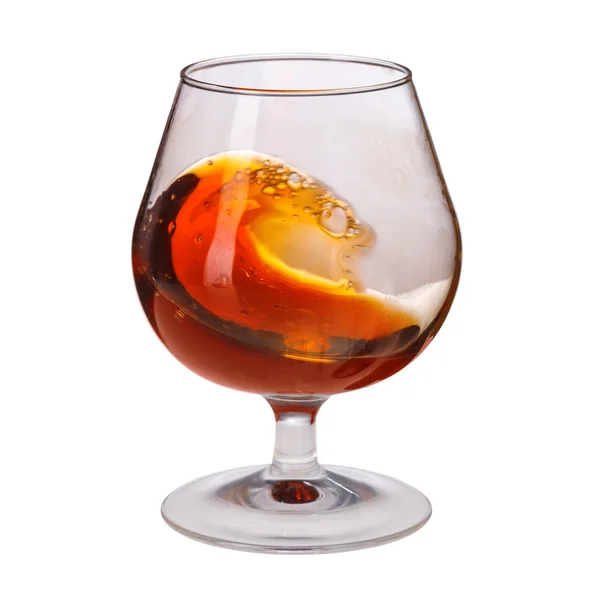 Splash van cognac in glas op witte achtergrond — Stockfoto