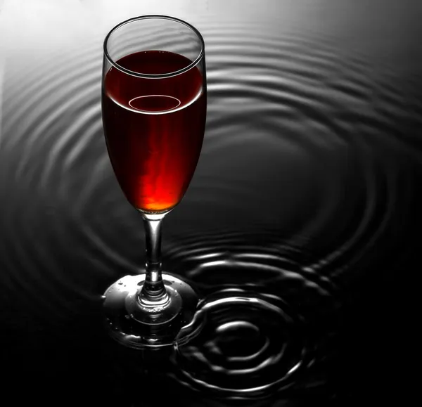 Copa de vino tinto sobre fondo de ondas de agua — Foto de Stock
