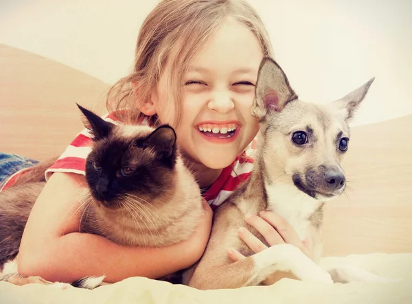 Ребенок обнимает кошку и собаку — стоковое фото