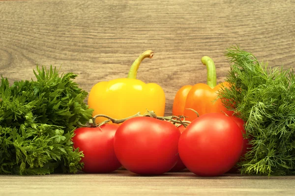 Tomates rojos, pimiento amarillo, perejil y eneldo sobre tablas de madera — Foto de Stock