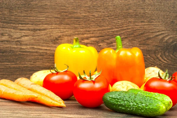 Tomates, pepinos, zanahorias y patatas sobre fondo de madera — Foto de Stock