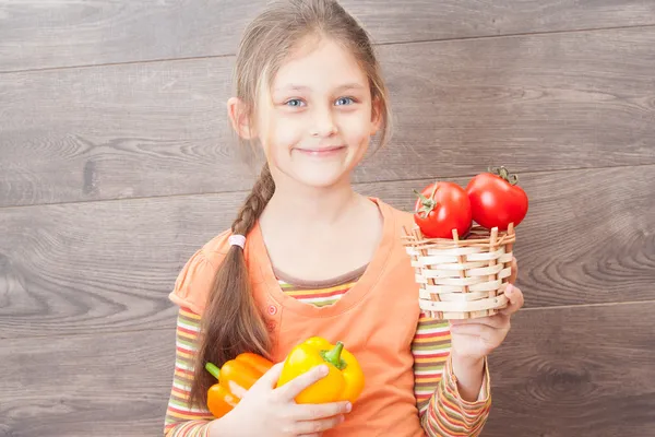 Beautiful girl holding a basket of tomatoes — Stock Photo, Image