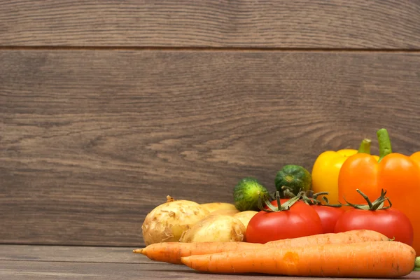 Peperoni, carote, patate, cetrioli e pomodori su una b di legno — Foto Stock