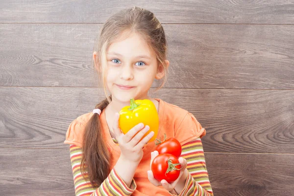 Beautiful little girl holding hands in raw vegetables — Stock Photo, Image