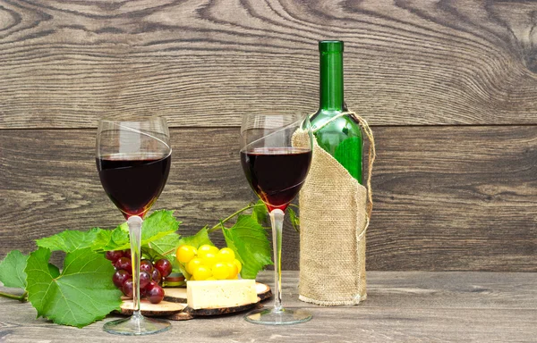 Dois copos de vinho tinto e frutas em fundo de madeira — Fotografia de Stock