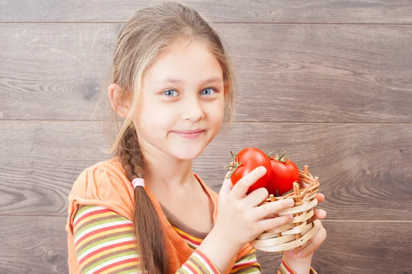 Child holding a wicker basket with tomatoes — Stock Photo, Image