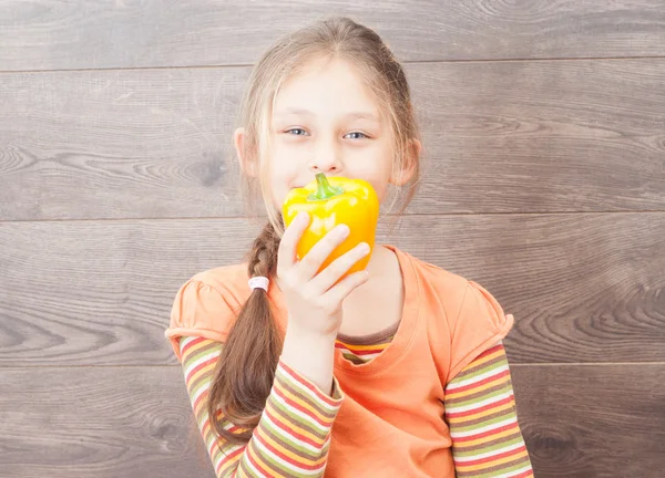 Little girl holding vegetables on a wooden background — Stock Photo, Image