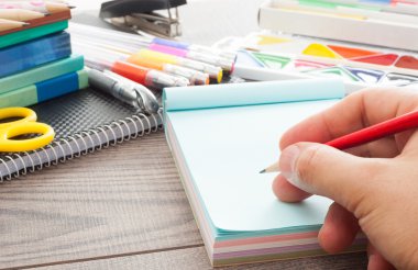 insan eli ahşap bir masa üzerinde bir defterde yazılı 