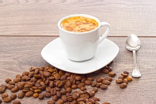 Cup of coffee and coffee beans on wooden table — Stock Photo, Image