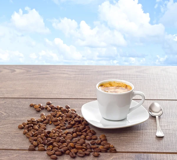 Cup of coffee and coffee beans on wooden table on background of — Stock Photo, Image