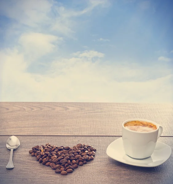 Cup of coffee and heart symbol made of coffee beans — Stock Photo, Image