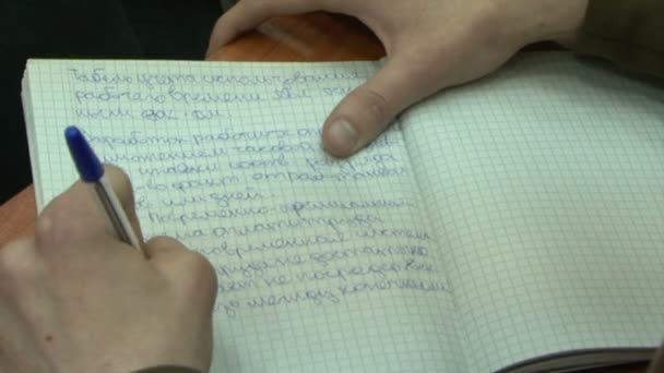 Hand van een vrouw schrijft met een pen in een notitieblok — Stockvideo