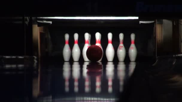 Bowling ball rolls and beats skittles lit in dark, closeup view — Stock Video