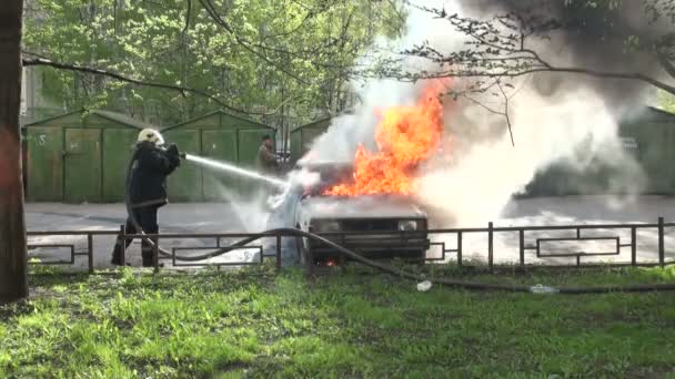 Brandweerlieden blussen verbrande auto op straat — Stockvideo