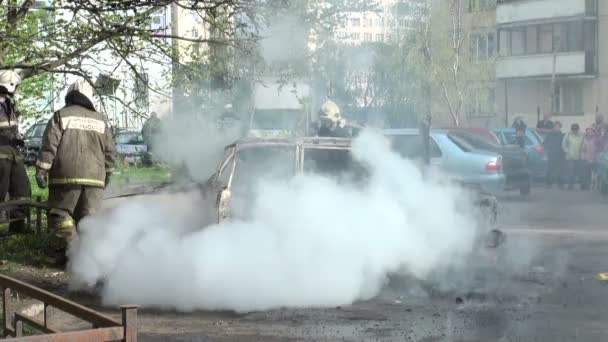 I vigili del fuoco estinguono l'auto bruciata sulla strada della città — Video Stock