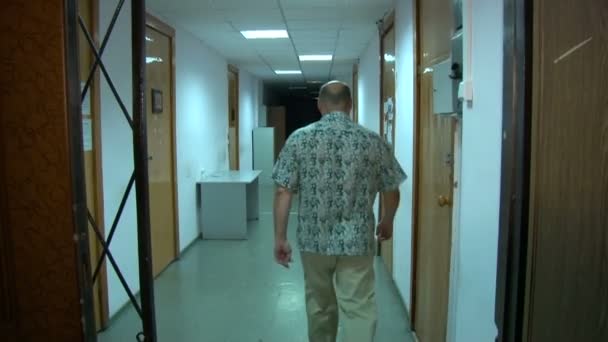 En man går längs korridoren — Stockvideo