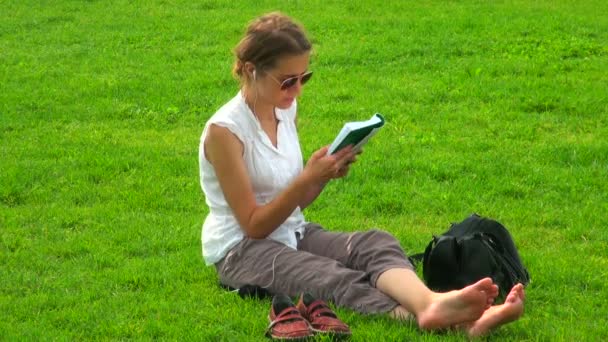 Girl with a book on the grass — Stock Video