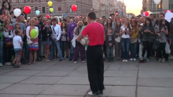 Hombre haciendo malabarismos pelota de fútbol en una calle frente a la multitud — Vídeo de stock