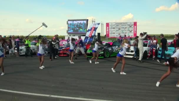 Équipe de filles dansant lors de courses de voitures — Video