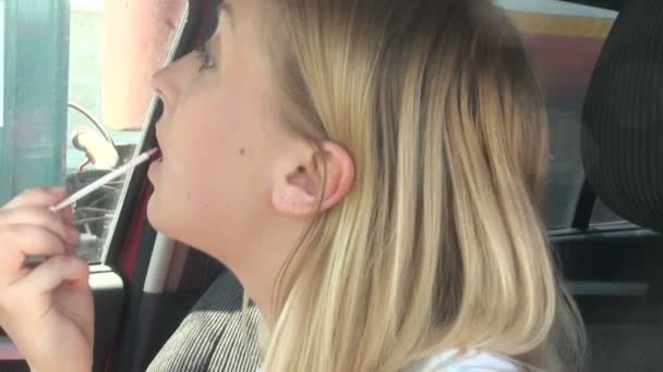 Blondine im Auto malt sich die Lippen — Stockvideo